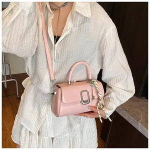 Pink leather handbag with oval metal clasp and scarf decoration on model