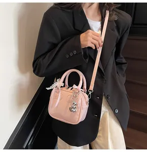 Detail of pink bowling bag featuring white lace, ribbon bow and silver heart charm