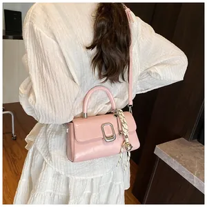 Pink PU leather crossbody bag with silver U-shaped buckle shown on model in white dress