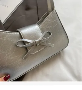 Detailed view of silver metallic bow handbag with crinkled leather texture for women