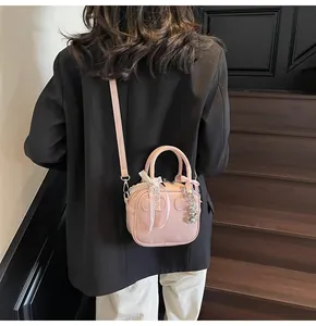 Pink bowling bag detail showing lace bow and heart metal pendant with shoulder strap