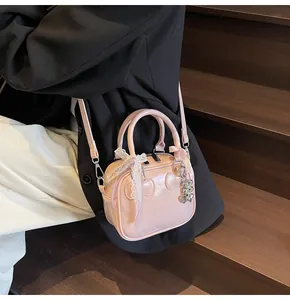 Detail of pink glossy handbag with lace bow, heart charm and adjustable shoulder strap