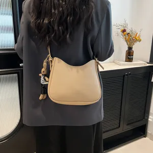 Minimalist beige pebble leather bucket bag with cute bear pendant shown on model