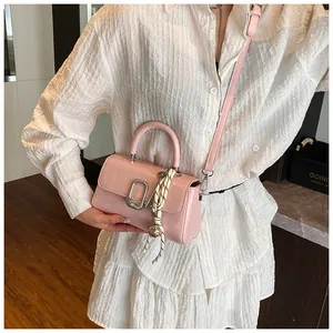 Detail of light pink leather square bag with silver clasp and braided knot charm