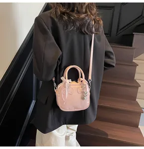 Detail of pink mini bowling bag with lace bow and heart charm on a shoulder strap