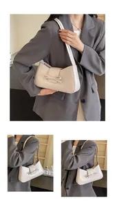 Detailed view of beige faux leather shoulder bag featuring bow decoration and grain texture