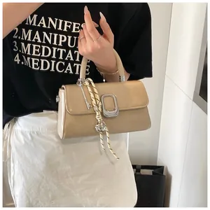 Detail of beige square handbag with silver buckle and striped woven lanyard accessory