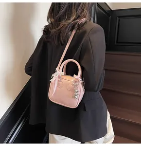Detail of pink bowling bag with lace bow and triple heart metal charms worn by a model