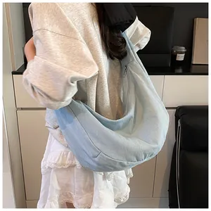 Vue détaillée du sac hobo en denim bleu clair montrant la grande capacité et le zip