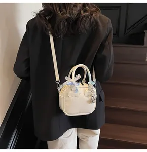 Close-up of creamy white glossy bowling bag with lace bow and silver bear charm detail