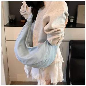Vue latérale du grand sac hobo bleu clair porté par un mannequin dans un décor épuré