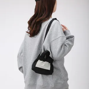 Piccola borsa a mano bicolore bianco e nero con logo del sole e tracolla casual