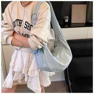 Détail du sac croissant en jean bleu clair avec bandoulière réglable et boucle métal