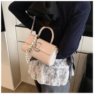 Close-up of beige crossbody bag with silver buckle, silk scarf and metal ball pendant