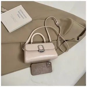 Detail of off-white minimalist crossbody bag with silver buckle on a khaki blazer