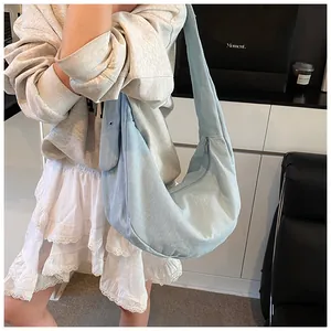 Détail du sac bandoulière en toile bleu clair avec large sangle et œillets métalliques