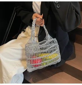 Detalle de bolso tejido metálico plateado con frutas en una escalera de madera moderna