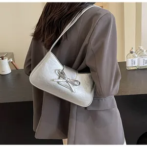 Detail of silver metallic bag with bow accent shown as a stylish underarm shoulder bag