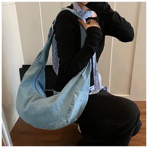 Détail d'un sac hobo en jean bleu clair avec large bandoulière réglable et boucles en métal