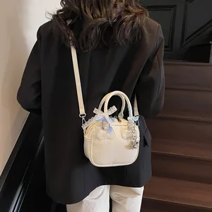 Chic off-white bowling handbag with lace bow and bear charm on wooden stairs