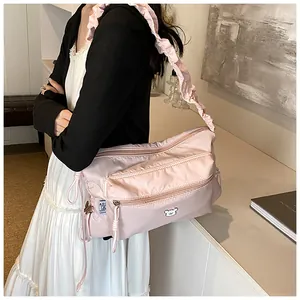 Détail du sac à cordon en nylon rose avec bandoulières froncées et emblème d'ours