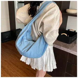 Vue détaillée d'un grand sac bandoulière en denim bleu porté par un mannequin