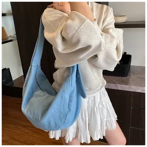 Vue détaillée du sac besace bleu clair en forme de croissant avec bandoulière large