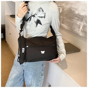 Détail du sac à bandoulière en nylon avec bandoulière plissée et écusson d'ours brodé
