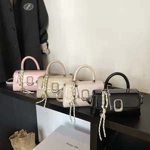 Minimalist square crossbody bags in pink, brown, and black displayed in a boutique setting