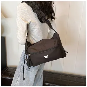Détail du sac à bandoulière en nylon noir avec sangle froncée et logo d'ours blanc