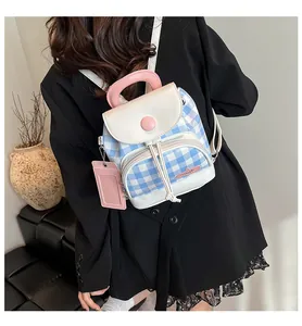 Detail of a mini blue checkered backpack with pink handle and a card holder charm accessory