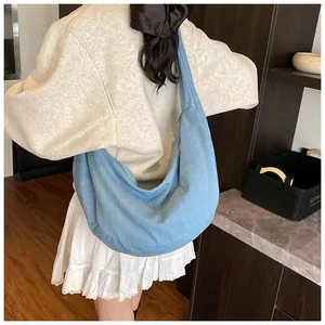 Vue détaillée du grand sac hobo en jean bleu clair porté par un mannequin