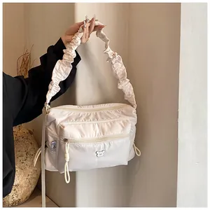 Détail du sac bandoulière en nylon avec bretelles plissées et logo ours argenté chic