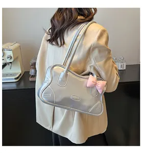 Detail of silver metallic tote bag with pink bow accent on a shoulder strap model