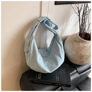 Gros plan d'un grand sac croissant bleu clair en toile texturée sur fond cuir
