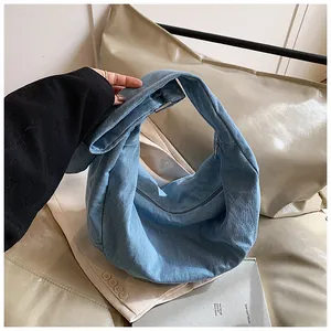 Détail du sac croissant en denim bleu clair montrant la texture douce et le zip