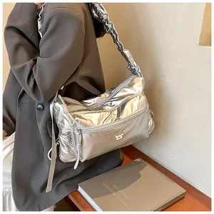 Détail du sac bandoulière matelassé argenté avec bandoulière à cordon et logo ours