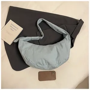 Détail du sac bandoulière demi-lune en toile gris-bleu clair avec boucle argentée