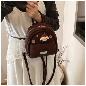 Detail of brown corduroy backpack featuring wooden buttons and cute cartoon character