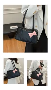 Detail of a black tote bag with a pink bow accent and sleek matte leather texture