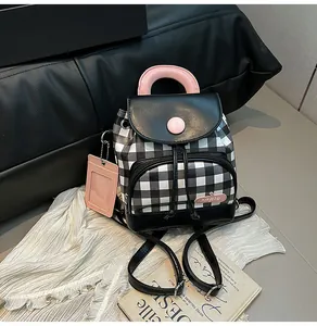 Detail of checkered mini backpack featuring pink handles and custom embroidery accents