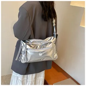 Sac bandoulière matelassé argenté brillant avec logo ours porté par un mannequin