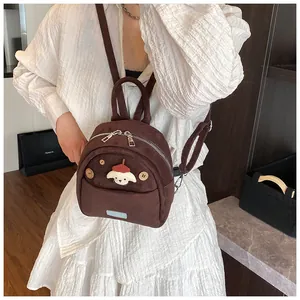 Detail of cute dark brown plush backpack featuring a white puppy head and silver hardware
