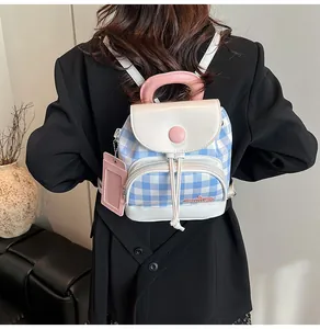 Rear view of a mini blue and white plaid backpack with pink handle on a black blazer