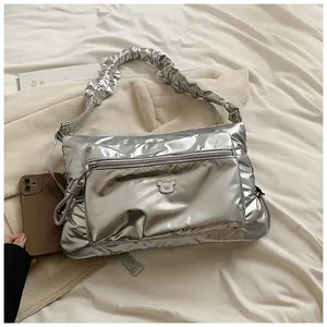Détail d'un sac à bandoulière en nylon argenté brillant avec poignées plissées et ours