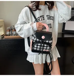 Detail of mini backpack with black and white grid pattern and pink accents in casual scene