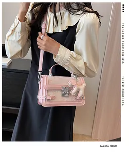 Close-up of pink leather handbag with silver lock buckle and cute plush dog pendant