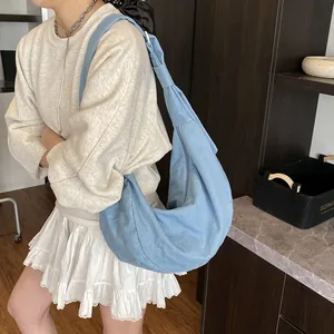 Grand sac bandoulière minimaliste en toile bleu clair porté par un mannequin en style décontracté
