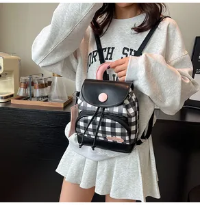 Detail of checkered canvas backpack featuring pink straps and drawstring closure
