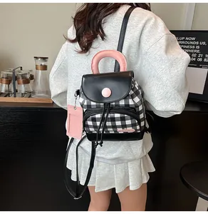 Detail of checkered backpack with pink handle and matching card holder on model